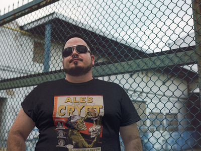 Ales from the Crypt Beer T-Shirt on Big Guy in Front of Fence